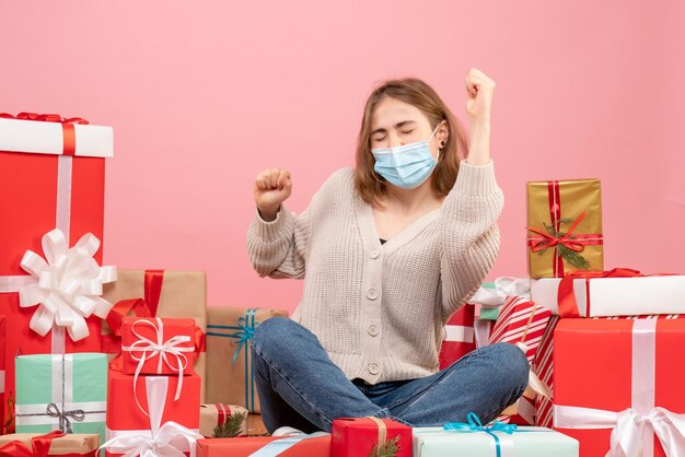 Vooraanzicht jonge vrouw zitten rond kerstcadeautjes in steriel masker