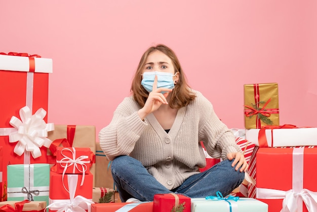 Vooraanzicht jonge vrouw zitten rond kerstcadeautjes in steriel masker