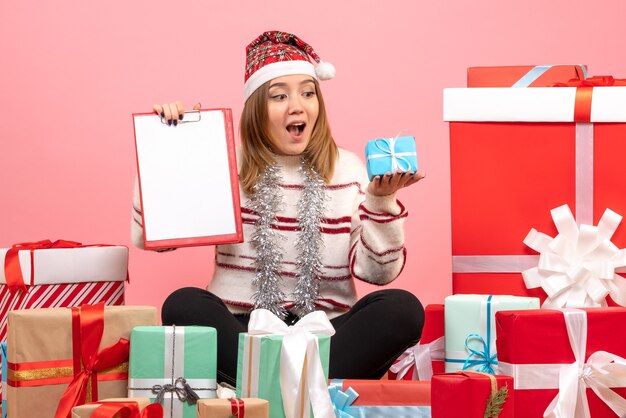 Vooraanzicht jonge vrouw zitten rond kerstcadeautjes met bestandsnota