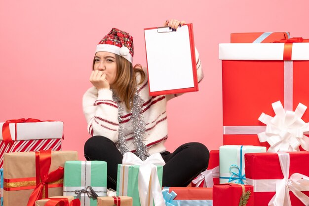 Vooraanzicht jonge vrouw zitten rond kerstcadeautjes met bestandsnota