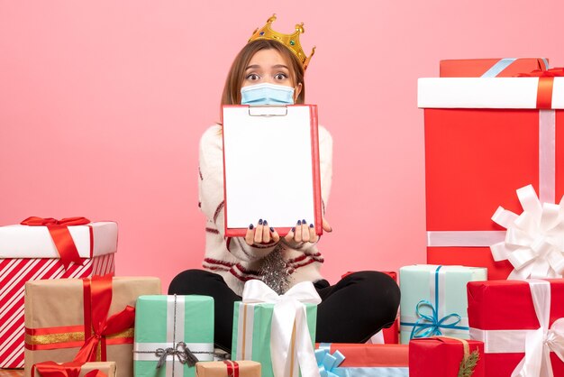 Vooraanzicht jonge vrouw zitten rond kerstcadeautjes met dossiernota