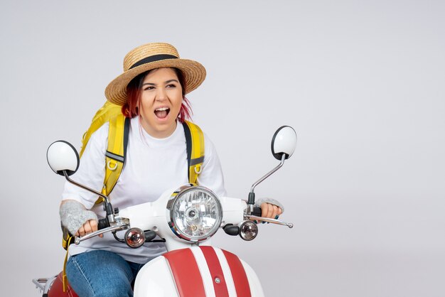 Vooraanzicht jonge vrouw zittend op motorfiets met rugzak en hoed witte muur