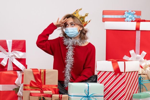 Vooraanzicht jonge vrouw zittend rond kerstcadeautjes in masker