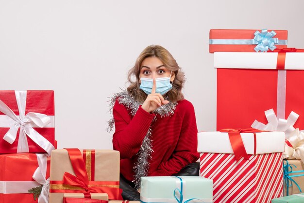 Vooraanzicht jonge vrouw zittend rond kerstcadeautjes in masker