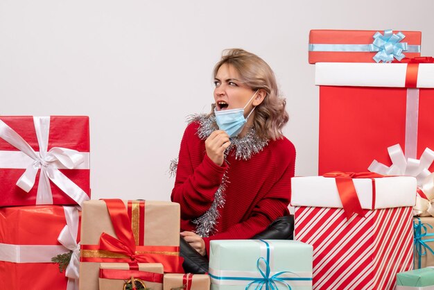 Vooraanzicht jonge vrouw zittend rond kerstcadeautjes