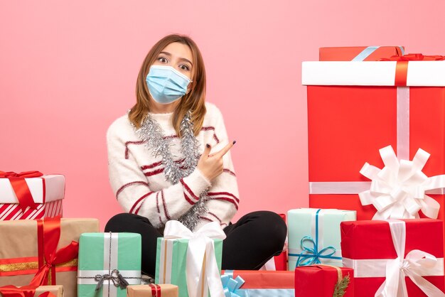 Vooraanzicht jonge vrouw zittend rond kerstcadeautjes