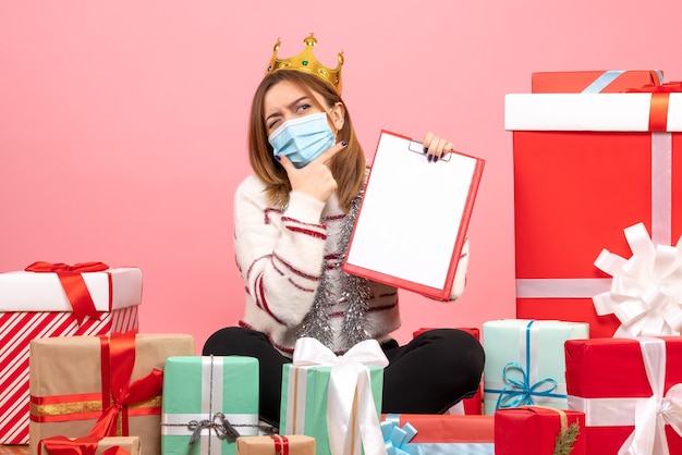 Vooraanzicht jonge vrouw zittend rond kerstcadeautjes