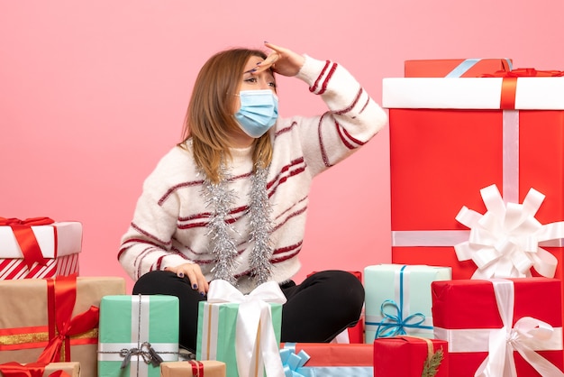 Vooraanzicht jonge vrouw zittend rond kerstcadeautjes