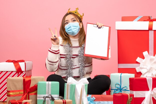 Vooraanzicht jonge vrouw zittend rond kerstcadeautjes