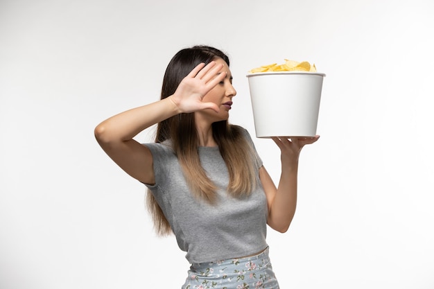 Vooraanzicht jonge vrouwelijke aardappelchips te houden tijdens het kijken naar film op wit oppervlak