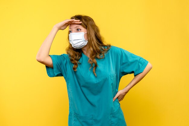 Vooraanzicht jonge vrouwelijke arts in masker op gele ruimte