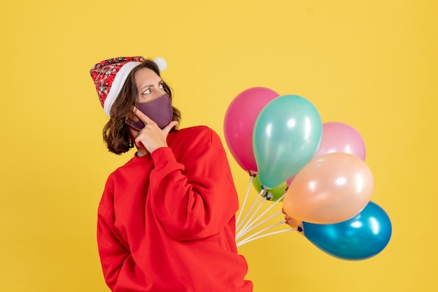 Vooraanzicht jonge vrouwelijke ballonnen verbergen in steriel masker kerst vrouw vakantie kleur emotie nieuwjaar