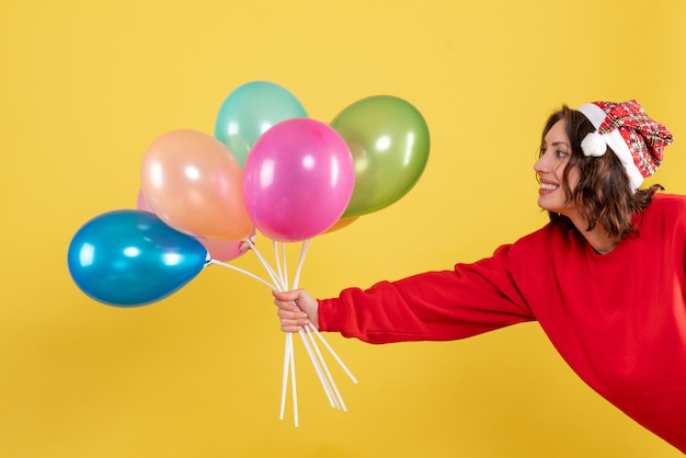 Vooraanzicht jonge vrouwelijke bedrijf ballonnen op geel