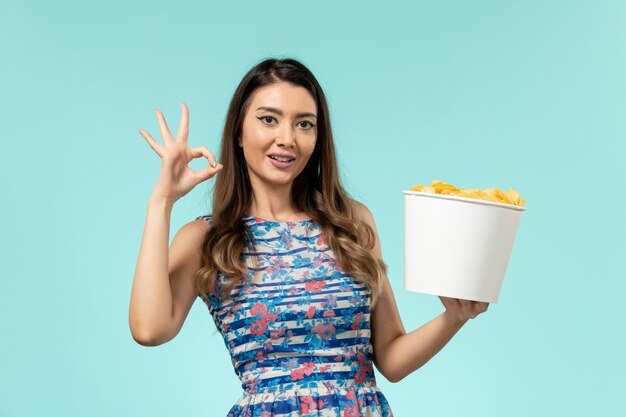 Vooraanzicht jonge vrouwelijke bedrijf mand met chips op het blauwe bureau