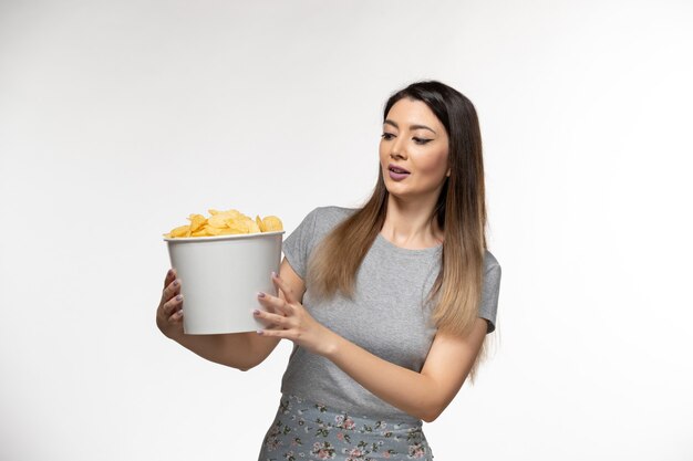 Vooraanzicht jonge vrouwelijke bedrijf mand met chips op wit oppervlak