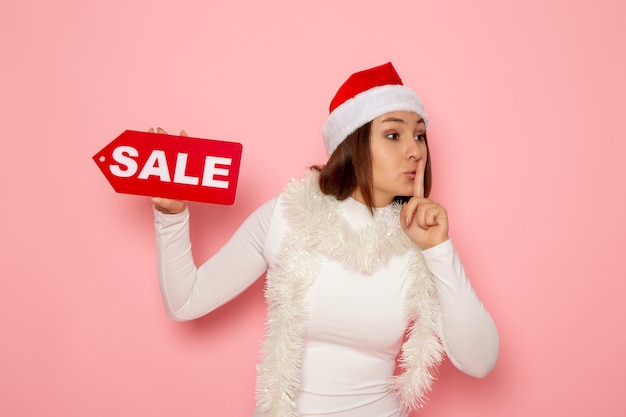 Vooraanzicht jonge vrouwelijke bedrijf verkoop geschreven figuur op roze muur vakantie kerstmis nieuwjaar mode sneeuw kleur
