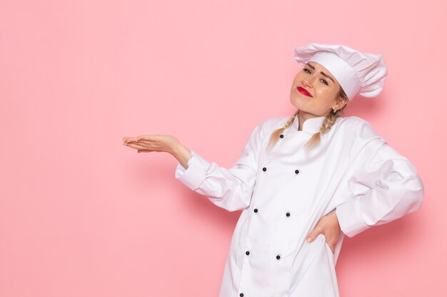 Vooraanzicht jonge vrouwelijke kok in witte kok pak poseren helemaal op de roze ruimte kok keuken werk foto