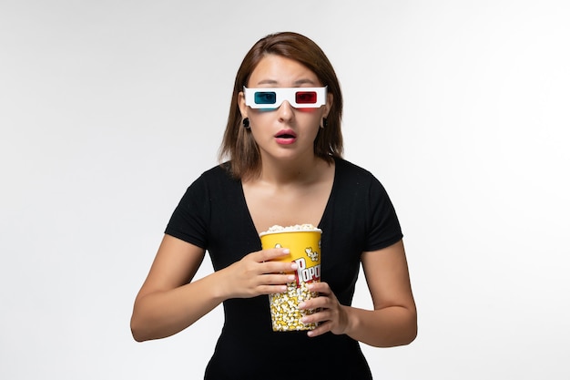Vooraanzicht jonge vrouwelijke popcorn in d zonnebril kijken naar film met aandacht op wit oppervlak