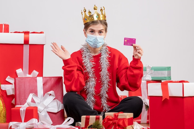 Vooraanzicht jonge vrouwelijke zitten met kerstcadeautjes in masker