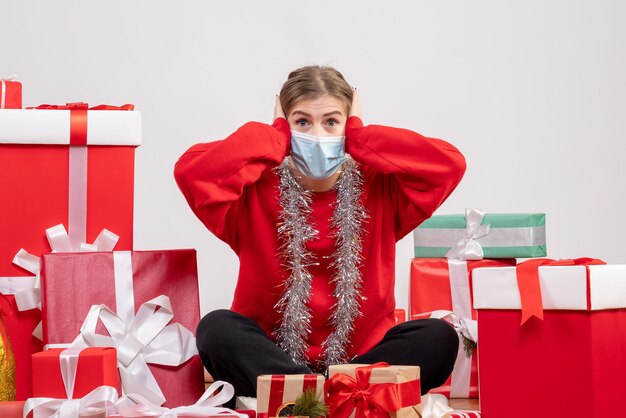 Vooraanzicht jonge vrouwelijke zitten met kerstcadeautjes in masker