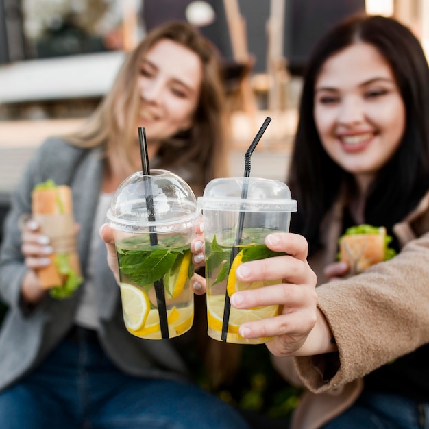 Vooraanzicht jonge vrouwen die genieten van enkele subs en cocktails