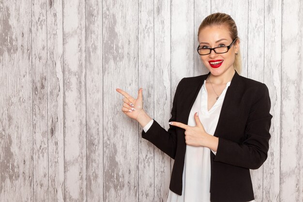 Vooraanzicht jonge zakenvrouw in strikte kleding zwarte jas met optische zonnebril op wit bureau werk job office vrouwelijke zakelijke bijeenkomst