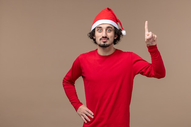 Vooraanzicht jongeman verhogen zijn vinger op de bruine achtergrond vakantie emoties kerst