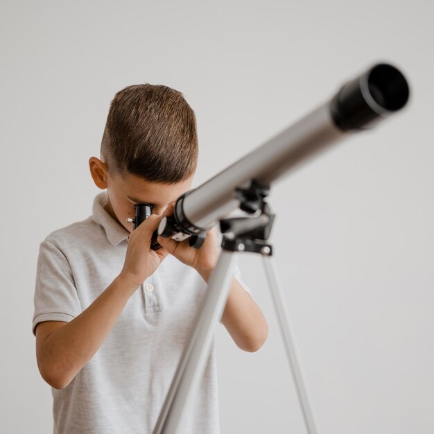 Vooraanzicht jongen met een telescoop in de klas