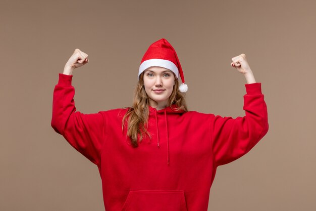 Vooraanzicht kerst meisje glimlachend en buigen op bruine achtergrond vakantie kerst emoties