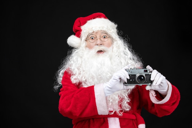 Vooraanzicht kerstman in klassiek rood pak met camera