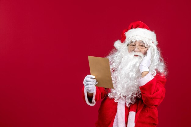 Vooraanzicht kerstman leest brief van kind op rode emotie presenteert kerstvakantie