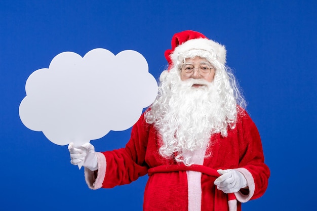 Gratis foto vooraanzicht kerstman met een groot wolkvormig bord op de blauwe sneeuwkerstkleur