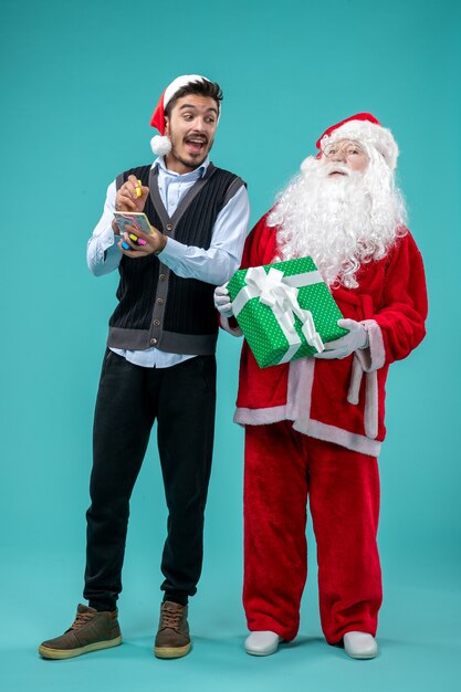 Vooraanzicht Kerstman met jonge man die aantekeningen maakt op de blauwe achtergrond