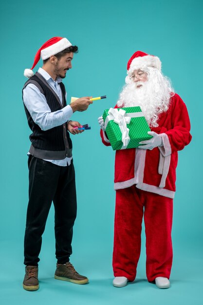 Vooraanzicht Kerstman met jonge man die aantekeningen maakt op de blauwe achtergrond