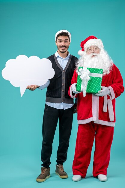 Vooraanzicht Kerstman met jonge mannelijke whos die wit wolkenteken op de blauwe achtergrond houdt