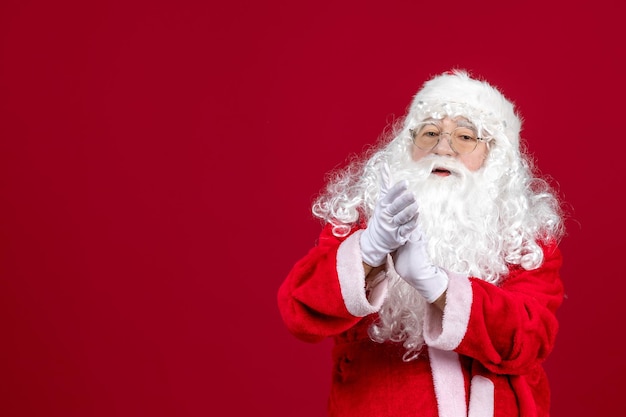 Vooraanzicht kerstman met klassieke witte beer en rode kleren die op een rood bureau staan, kerstmis nieuwjaar