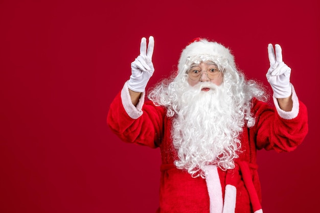 Vooraanzicht kerstman met klassieke witte beer en rode kleren op rode bureauvakantie nieuwjaar