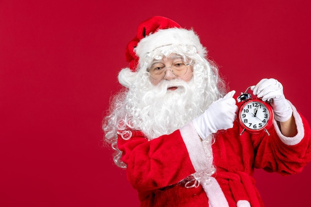 Vooraanzicht kerstman met klok op rode bureau kerstvakantie