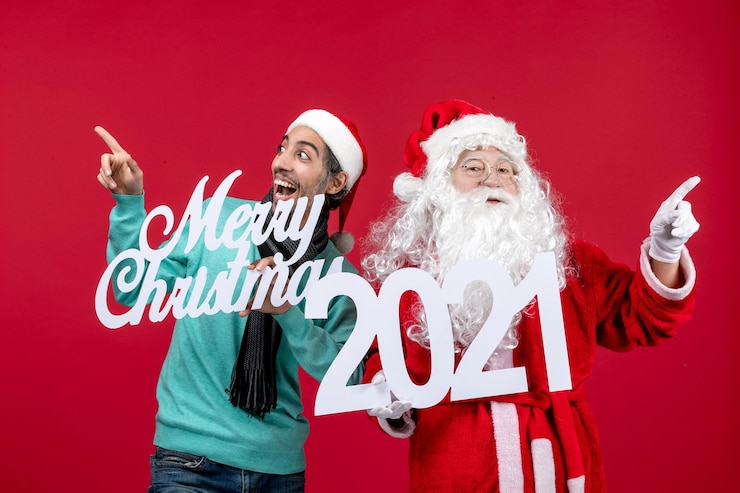 Gratis Foto vooraanzicht kerstman met mannelijke holding en vrolijke kerstgeschriften over rode kerstkleurvakantie