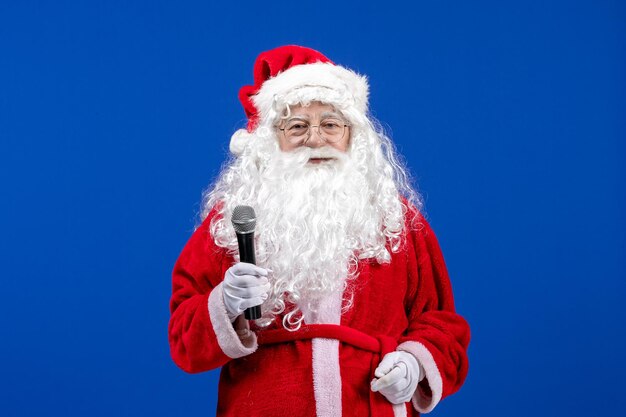 Vooraanzicht kerstman met rood pak en witte baard met microfoon op blauwe kleur nieuwjaarsvakantie xmas