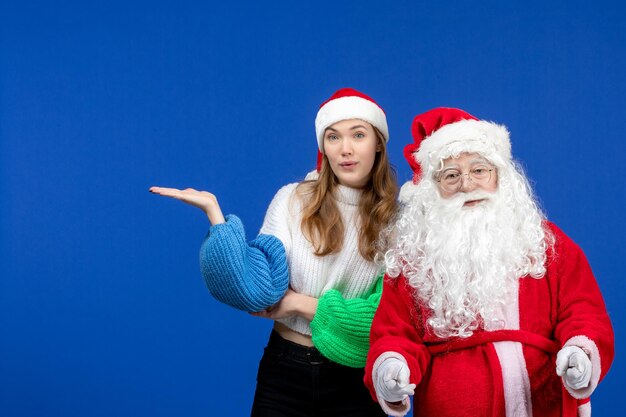 Vooraanzicht Kerstman samen met jonge vrouw staande op blauwe vloer nieuwjaar vakantie kleur