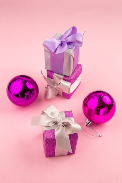 Gratis foto vooraanzicht kleine cadeautjes met kerstboomspeelgoed op de roze tafel
