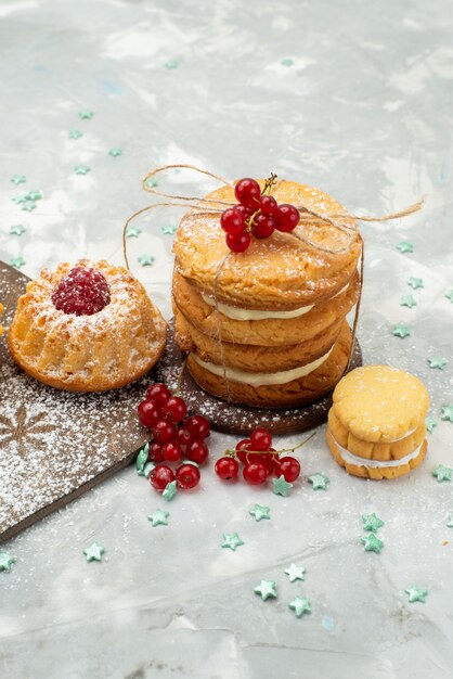 Vooraanzicht kleine d cakes met room en sandwichkoekjes op de lichte suiker van de oppervlakte zoete thee