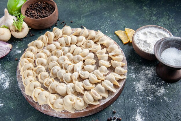 Vooraanzicht kleine dumplings met bloem op donkergrijs oppervlak