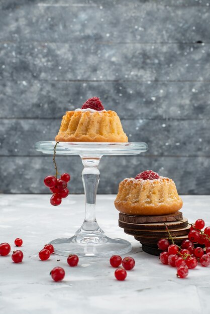 Vooraanzicht kleine heerlijke cakes met room en rode veenbessen op de lichte oppervlaktecake