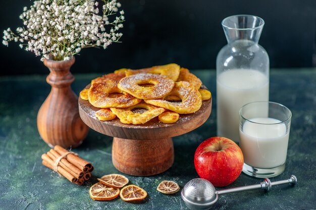 Vooraanzicht kleine heerlijke taarten in de vorm van een ananasring met melk op donkere hotcake bak fruittaart gebak kleur biscuit cookie cake