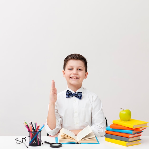 Vooraanzicht kleine jongen op bureau lezen