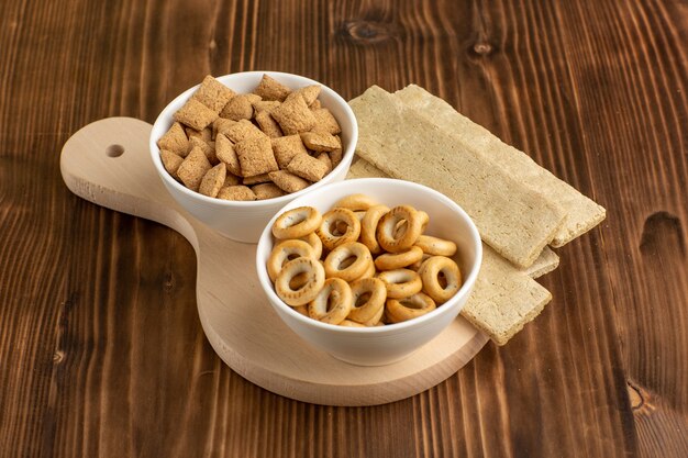 Vooraanzicht kleine kussenkoekjes met crackers op het bruine bureau