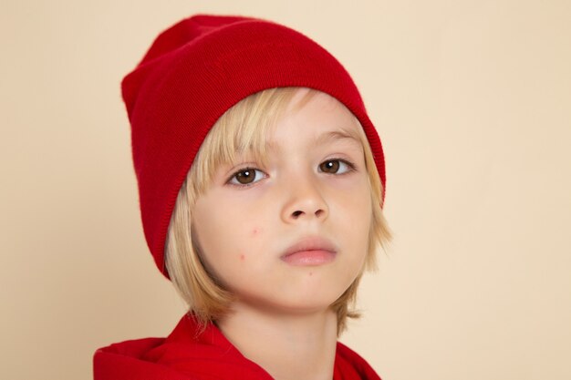 Vooraanzicht kleine schattige jongen in rood shirt en pet op witte muur