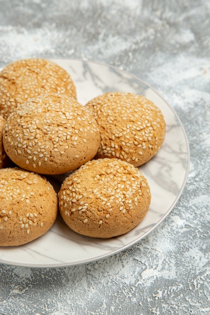 Gratis foto vooraanzicht kleine zachte koekjes heerlijk dessert voor thee in plaat op lichte witte muur biscuit cake bakken suiker zoet koekje